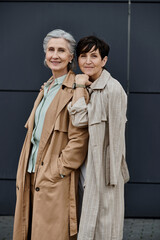 A mature beautiful lesbian couple standing together in front of a building.
