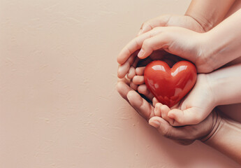 Adult and child hands holding a red heart on an aqua background symbolize heart health, donation, corporate social responsibility, World Heart Day, World Health Day, and Family Day.