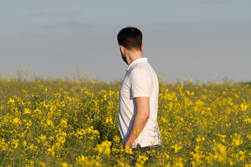 Fototapeta premium Embracing Summer's Vitality: Joyful Man Standing in Blooming Rapeseed Meadow
