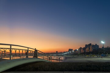 Bridge over water channel nº6 during sunset at the beach. In the background, the strip of sand and the buildings on the coast of the city of Santos, Brazil.