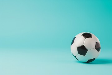 Naklejka premium A classic black and white soccer ball rests on a blue background, ready for action.