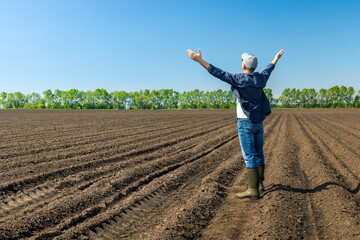  happy farmer standing in field with hands raised.  Concept of successful in agricultural business.