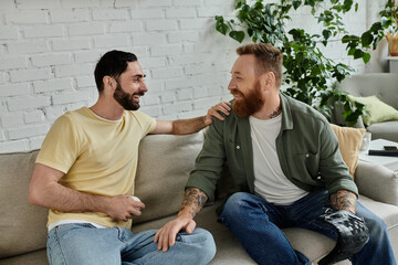 Two bearded men chat on a cozy couch watching a sports match, enjoying quality time together.