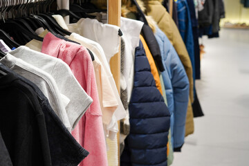 A rack of various clothes including t-shirts, jackets, and sweaters in different colors and...