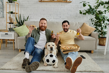 Two men, a bearded gay couple, sit on a couch eating pizza and drinking beer. A Labrador dog joins them in their cozy living room.