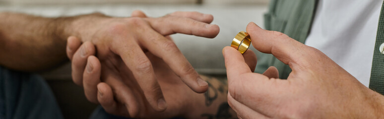 Fototapeta premium A bearded gay couple holding hands, showcasing a gold wedding ring on their fingers.