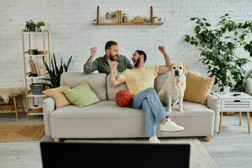 Two men, one with a beard, sitting on a couch with a dog, enjoying a relaxing moment in their...