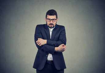 Young business man wearing a suit shaking and freezing 