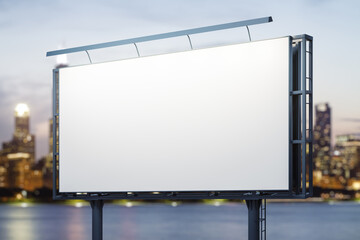 Fototapeta premium Blank white horizontal billboard on skyline background at evening, perspective view. Mock up, advertising concept