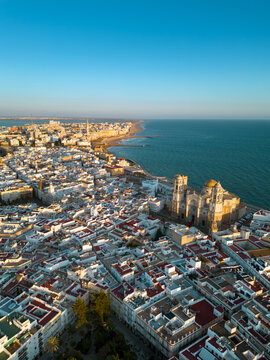 Aerial view of Cadiz city at sunset. City center with spectacular Cathedral of Cadiz in the middle. Medieval and historic city. Famous travel destination. Atlantic Ocean in background. Vertical photo