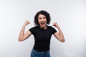 Happy joyful curly brunette woman clenched her fists