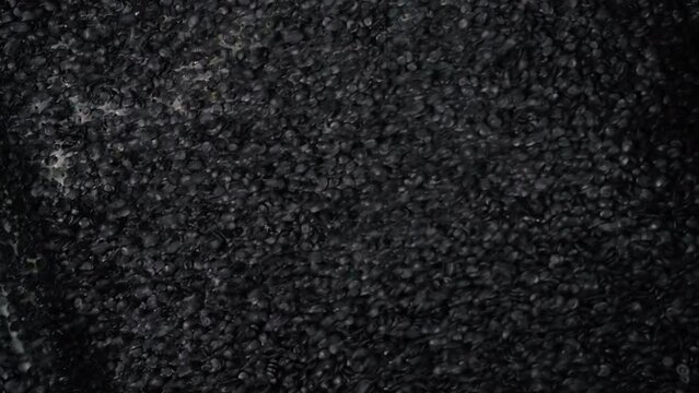 Conveyor equipment deals with plastic pellets processing at a production plant. Automated processing of huge amounts of plastic material pellets. Processing small black plastic pellets.