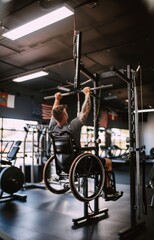 Naklejka premium Adaptive Fitness. Muscular man in a wheelchair actively training in fitness gym. Physiotherapy and rehabilitation