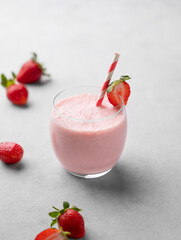 A glass of fresh strawberry smoothie on a light background with fresh berries.