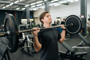 Closeup portrait of motivated beginner sportsman hard time performing barbell shoulder press in...