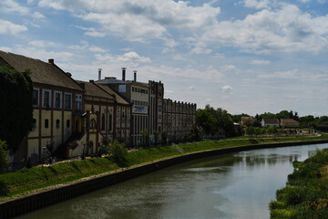 The embankment along the canal. An old abandoned beer factory near the river. A warm sunny spring day. A small town in Serbia is Zrenjanin. Vojvodina District.