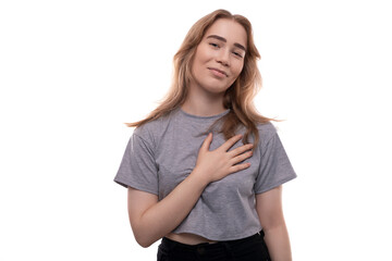 Confused fair-haired teenage girl in a gray T-shirt on a white background