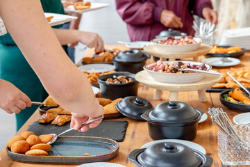 People enjoying a buffet-style meal, serving themselves from a variety of dishes including appetizers and snacks, creating a casual and inviting atmosphere for social dining.