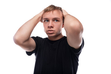 A teenage guy with blond hair dressed in a black T-shirt is worried about a problem