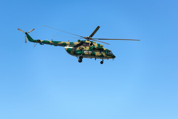 Big attack twin-engine multi-purpose helicopter military colors used for landing troops and their fire support and transporting ammunition and other cargo in blue sky
