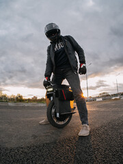 A man in a motorcycle outfit is preparing for a trip on a monowheel. Mobile urban transport © pavelkant