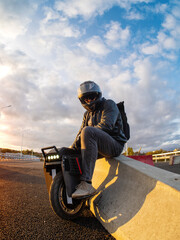 A rider wearing a helmet on an electric monowheel . Modern urban transport . At sunset © pavelkant