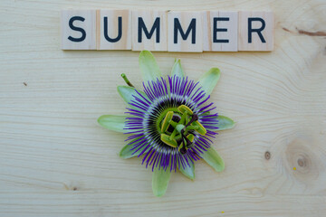 Passionflower flower and the inscription summer on a wooden background. Top view.