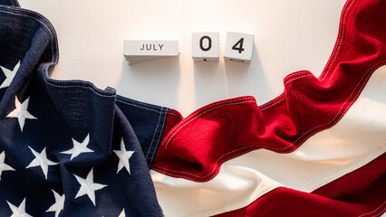 A close-up image of a folded American flag with wooden calendar blocks displaying the date July 4th.