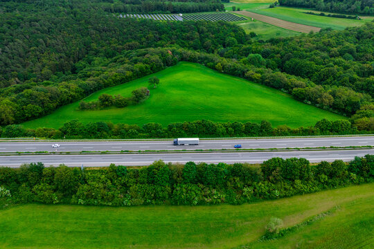 cargo truck on the highway. asphalt road among green fields and beautiful clouds. cargo delivery and transportation concept