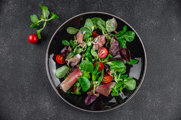 jamon salad green leaf lettuce, tomato, salad dressing appetizer meal food snack on the table copy space food background rustic top view keto or paleo diet