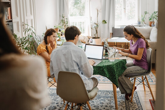 Siblings studying together while sitting on table in living room at home
