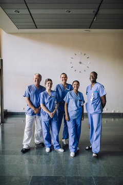 Portrait of smiling diverse healthcare team in blue scrubs standing together at hospital