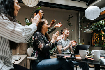 Happy male and female business professionals congratulating in team meeting at office