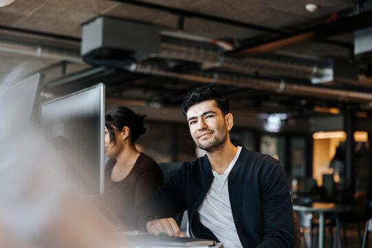 Portrait of smiling male entrepreneur with female colleague at office