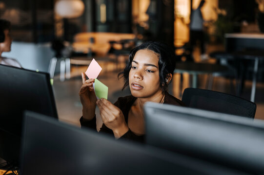 Young female entrepreneur reading adhesive notes at office