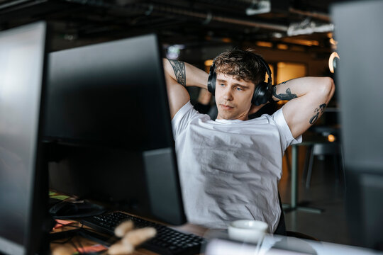 Tired male entrepreneur stretching arms while sitting at desk in office