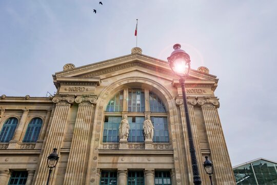 Facade of the Gare Du Nord train station showing two statues: Douai and Dunkerque. Lampposts typical of the city. Paris, France. 