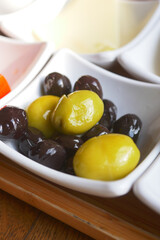 Collection of black and green olives with leaves.