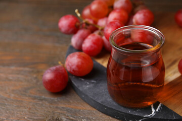 Wine vinegar in glass jar and grapes on wooden table