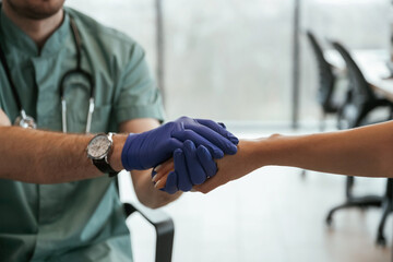 Blue gloves. Two doctors are holding hands indoors