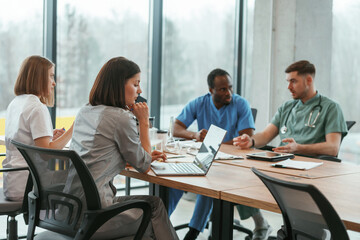 By the table. Group of doctors are together indoors