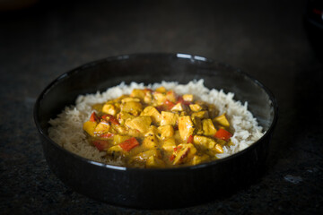 fresh cooking at home - sliced chicken with curry cream sauce and rice, served in a black bowl