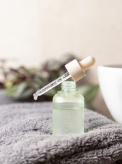 Pipette set on a green glass bottle put on dark grey towel near basin and green plant