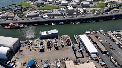 Shipyard beside interstate highway with cars traveling past coal refinery and boats in harbor 