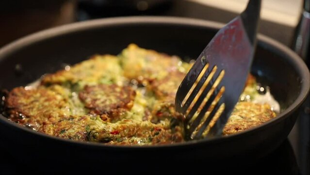 Zucchini balls frying in oil in a pan. 