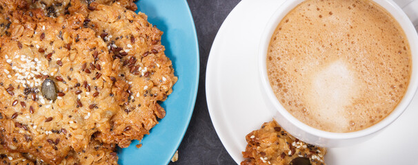 Cup of coffee with milk and fresh baked oatmeal cookies with honey and healthy seeds. Delicious crunchy dessert