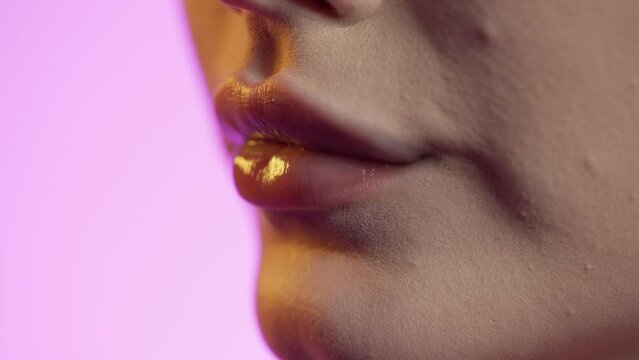 Zbliżenie na umalowane błyszczykiem kobiece usta 