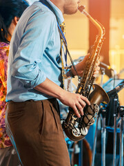 Musician playing saxophone on blurred background. Man with friends blow saxophone with the band for...