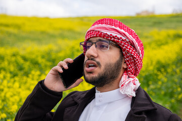 young arabic male making phone call during vacation in park, working from anywhere and stay...