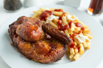 Halbes Hähnchen und Pommes Frites mit Ketchup und Mayonaise.
